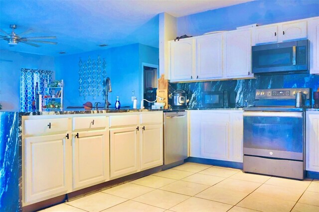 kitchen featuring white cabinets, appliances with stainless steel finishes, decorative backsplash, sink, and light tile patterned floors