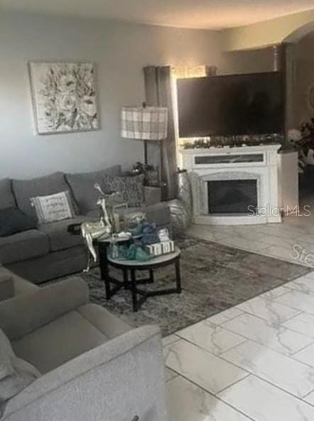 living area with marble finish floor and a fireplace