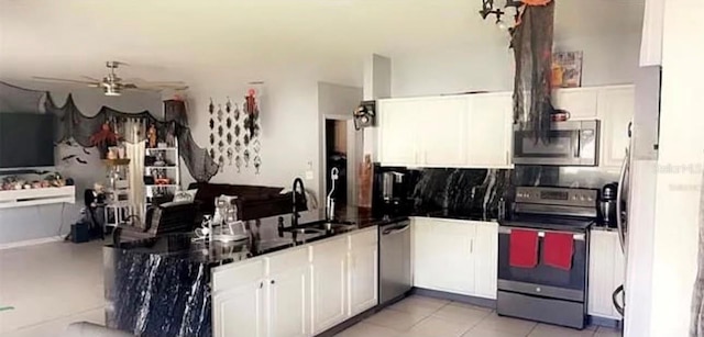 kitchen featuring ceiling fan, decorative backsplash, white cabinets, stainless steel appliances, and a sink