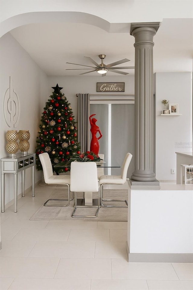 dining room featuring tile patterned floors, decorative columns, arched walkways, and a ceiling fan