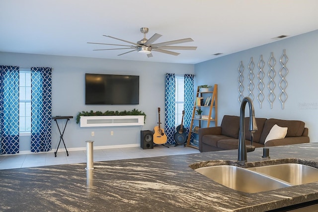 living room featuring tile patterned flooring, a ceiling fan, visible vents, and a wealth of natural light