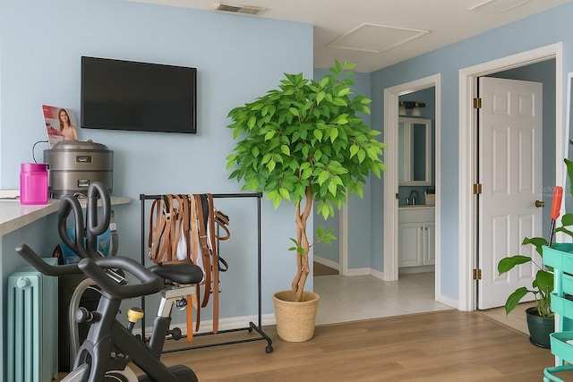exercise area featuring attic access, wood finished floors, visible vents, and a sink