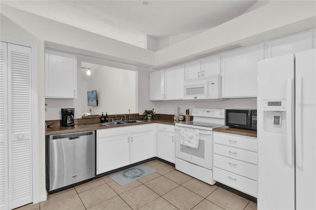 kitchen with light tile patterned floors, sink, white appliances, and white cabinets