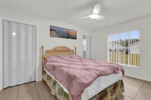 tiled bedroom with ceiling fan, a textured ceiling, and a closet