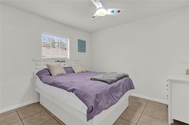 bedroom featuring ceiling fan, a textured ceiling, and light tile patterned floors