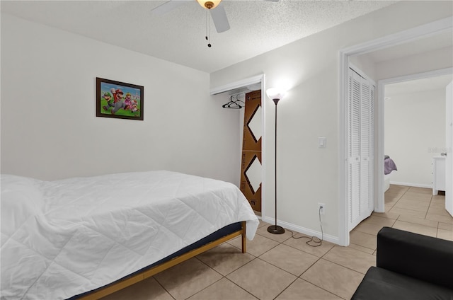 tiled bedroom with ceiling fan, a textured ceiling, and a closet