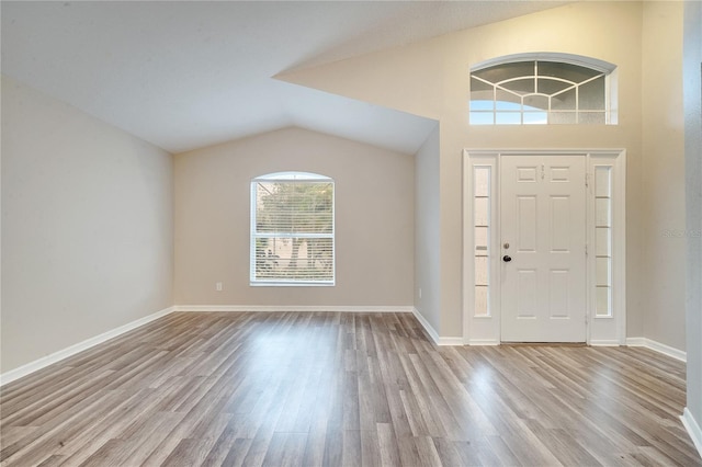 foyer entrance with light wood-type flooring and vaulted ceiling