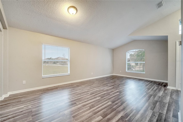 unfurnished room with wood-type flooring, a textured ceiling, and vaulted ceiling