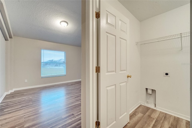 clothes washing area with a textured ceiling, hookup for an electric dryer, and hardwood / wood-style floors