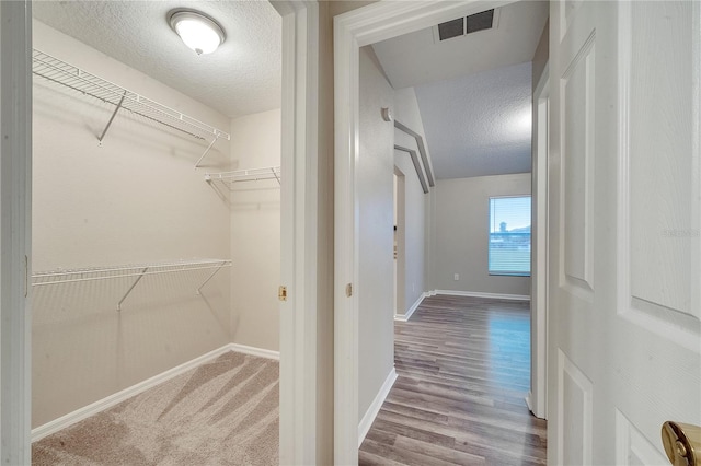 walk in closet featuring hardwood / wood-style flooring and vaulted ceiling