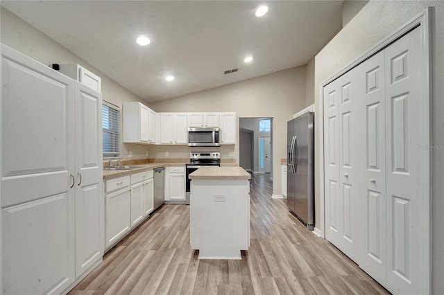 kitchen with a center island, light wood-type flooring, appliances with stainless steel finishes, and white cabinetry