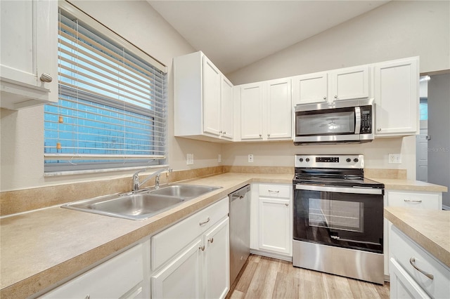 kitchen featuring stainless steel appliances, sink, white cabinets, vaulted ceiling, and light hardwood / wood-style flooring