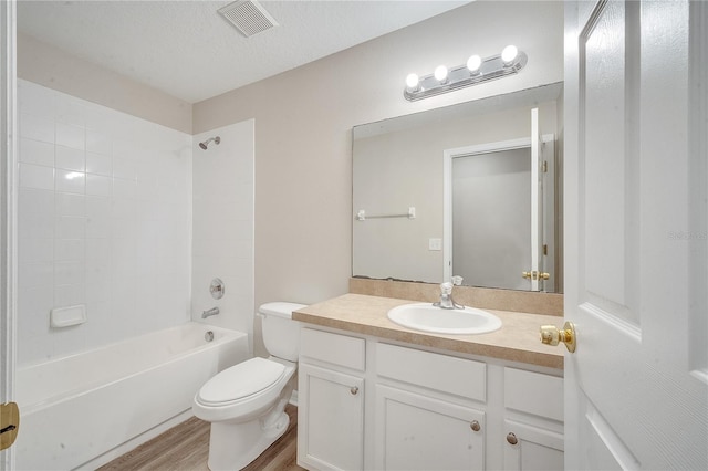 full bathroom featuring toilet, a textured ceiling, hardwood / wood-style floors, tiled shower / bath combo, and vanity