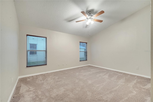 carpeted empty room with lofted ceiling, a healthy amount of sunlight, a textured ceiling, and ceiling fan