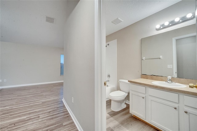 full bathroom with hardwood / wood-style flooring, vanity, washtub / shower combination, and toilet