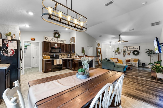 dining area with ceiling fan with notable chandelier, sink, and vaulted ceiling