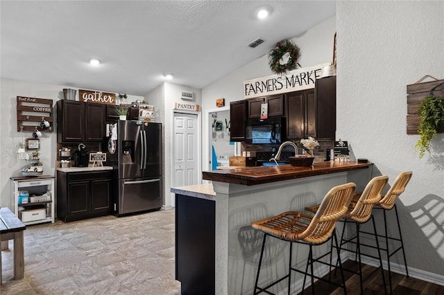 kitchen featuring kitchen peninsula, a kitchen bar, and stainless steel fridge with ice dispenser