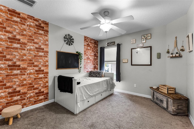 carpeted bedroom with ceiling fan, a textured ceiling, and brick wall