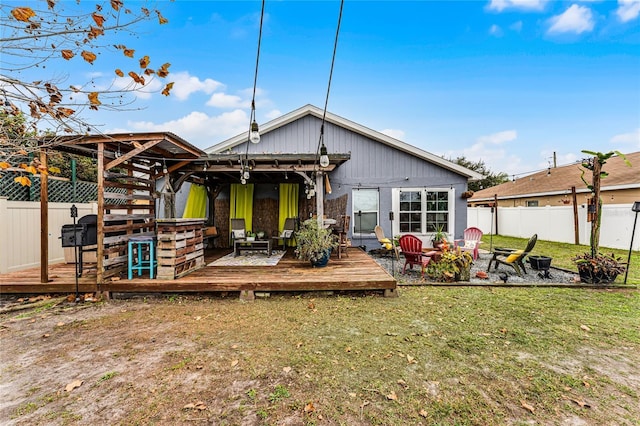 back of property featuring a deck, a yard, and a fire pit