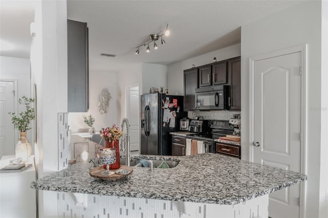 kitchen featuring sink, kitchen peninsula, light stone counters, and black appliances