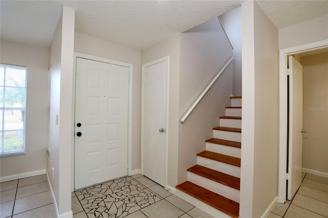 foyer featuring plenty of natural light, light tile patterned floors, and a textured ceiling