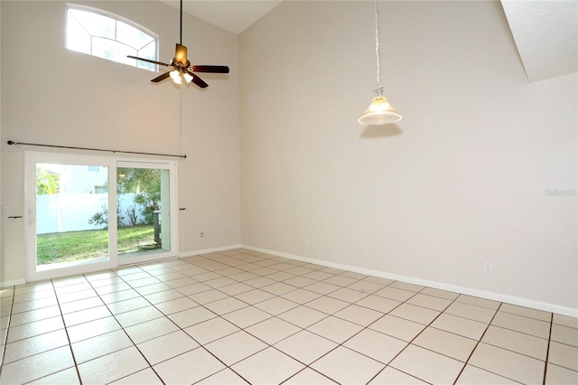 empty room featuring ceiling fan, plenty of natural light, light tile patterned floors, and a towering ceiling