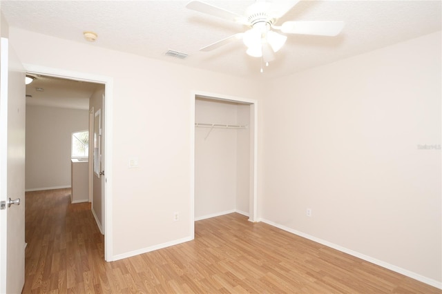 unfurnished bedroom with light hardwood / wood-style flooring, ceiling fan, a closet, and a textured ceiling