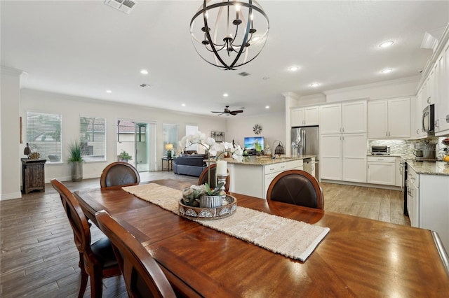 dining space featuring ceiling fan with notable chandelier, light hardwood / wood-style floors, sink, and crown molding