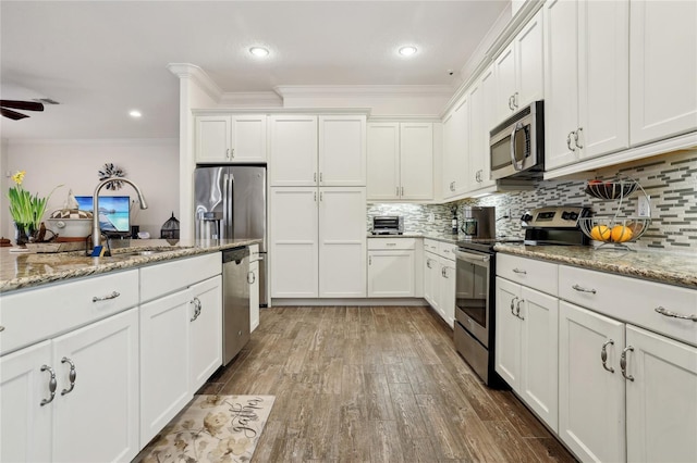 kitchen featuring light stone counters, white cabinetry, appliances with stainless steel finishes, and crown molding