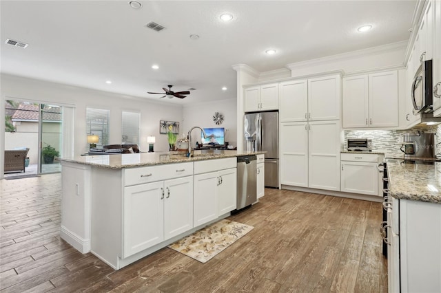 kitchen with ceiling fan, white cabinetry, light stone countertops, appliances with stainless steel finishes, and an island with sink