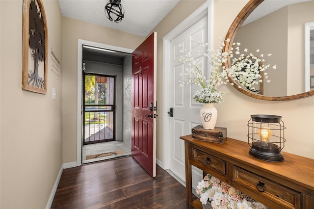 foyer entrance featuring a textured ceiling and dark wood-type flooring