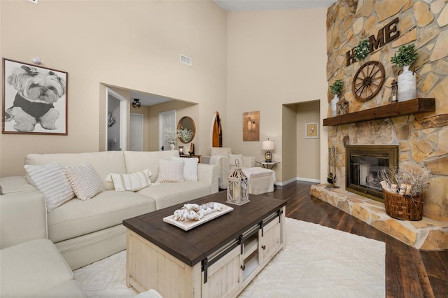 living room featuring hardwood / wood-style floors, a high ceiling, and a stone fireplace