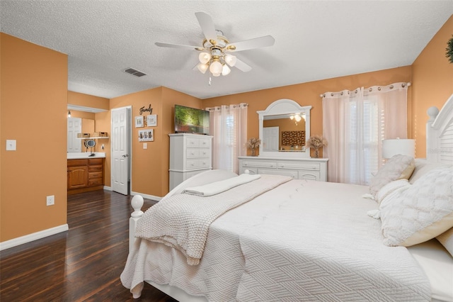 bedroom with ceiling fan, dark wood-type flooring, connected bathroom, and a textured ceiling