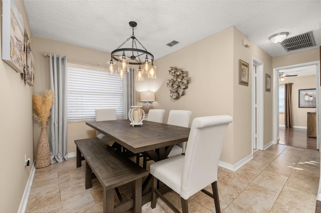 dining area with ceiling fan with notable chandelier and a textured ceiling