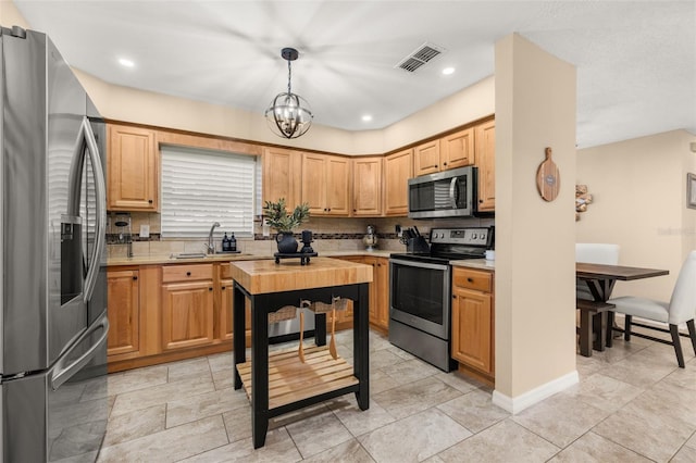 kitchen featuring appliances with stainless steel finishes, hanging light fixtures, decorative backsplash, sink, and an inviting chandelier