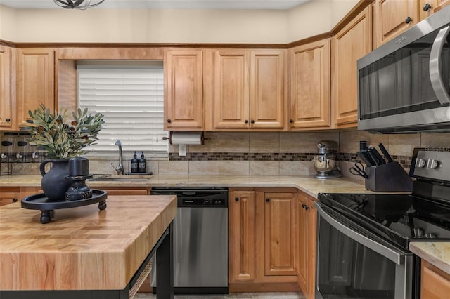 kitchen featuring appliances with stainless steel finishes, sink, decorative backsplash, and butcher block counters