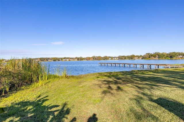 view of dock with a lawn and a water view