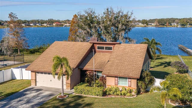 view of front facade with a front yard, a garage, and a water view