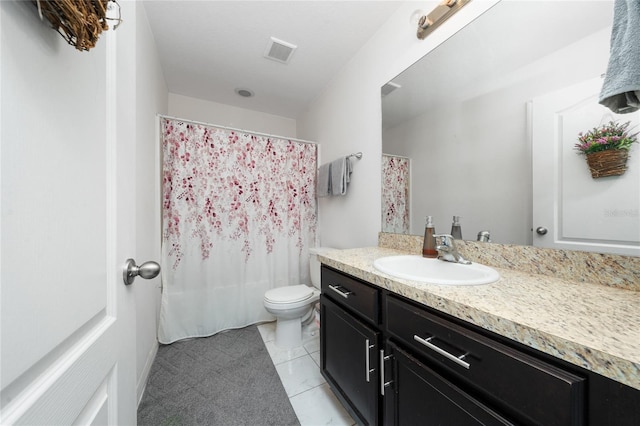 bathroom with toilet, vanity, and tile patterned floors