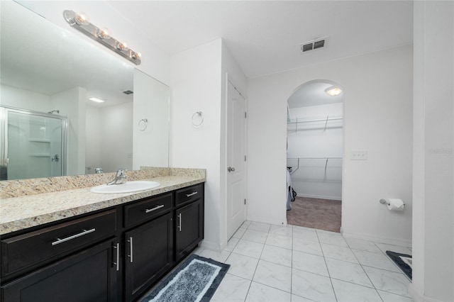 bathroom with a shower with shower door and vanity