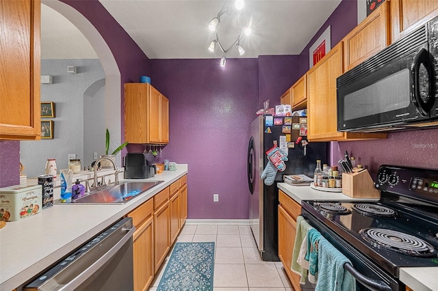 kitchen featuring light tile patterned floors, sink, rail lighting, and black appliances