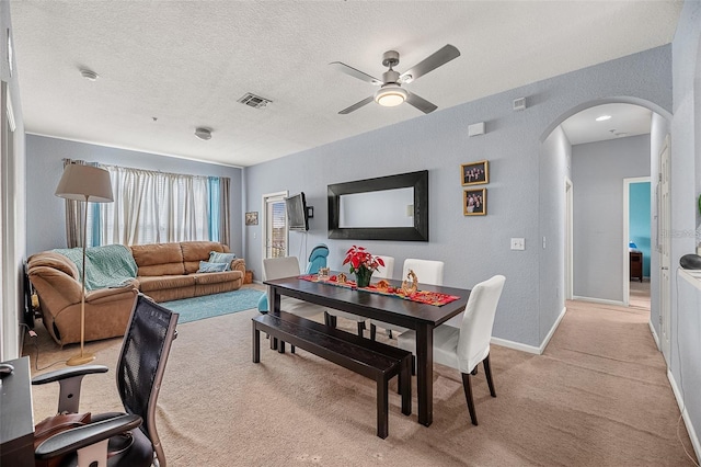 carpeted dining area with ceiling fan and a textured ceiling