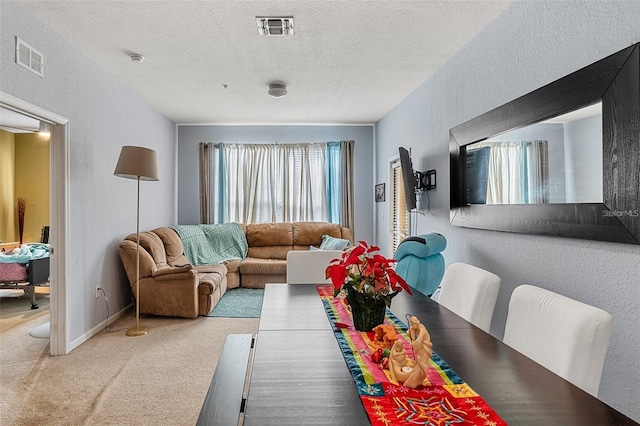 dining room with light colored carpet and a textured ceiling