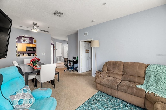 living room with ceiling fan, carpet floors, and a textured ceiling