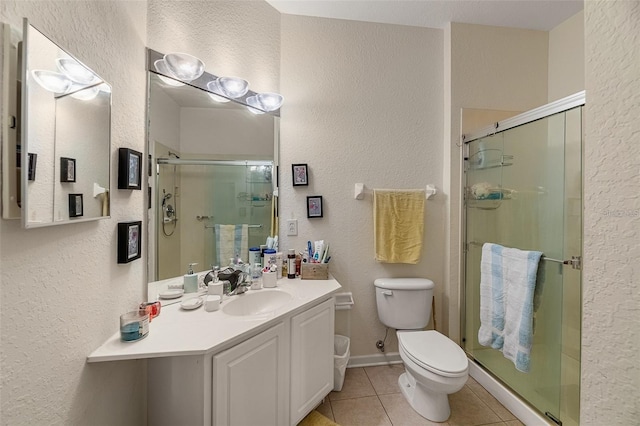 bathroom with a shower with shower door, toilet, vanity, and tile patterned flooring