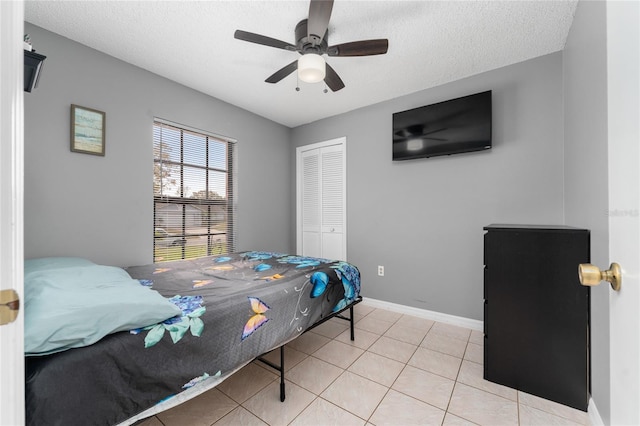 bedroom featuring light tile patterned flooring, a closet, ceiling fan, and a textured ceiling