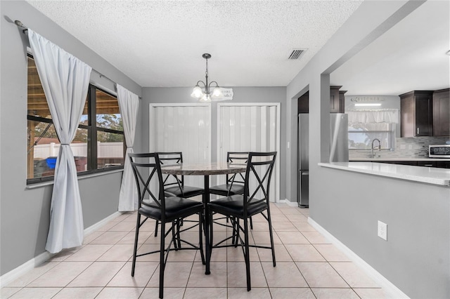 dining area featuring sink, a textured ceiling, a chandelier, and light tile patterned floors