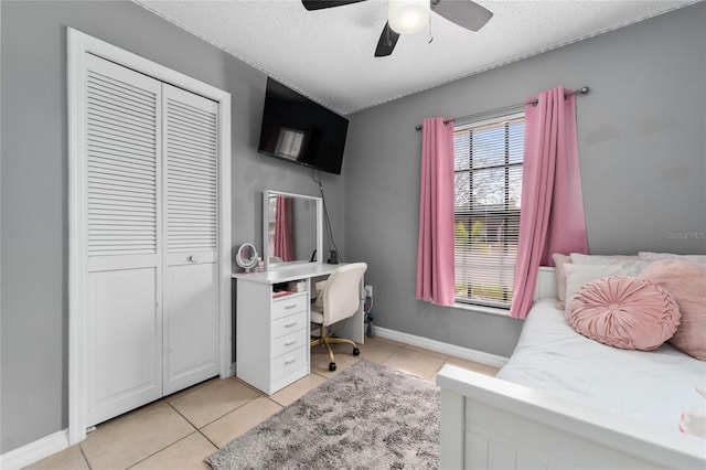 bedroom with ceiling fan, light tile patterned flooring, a textured ceiling, and a closet