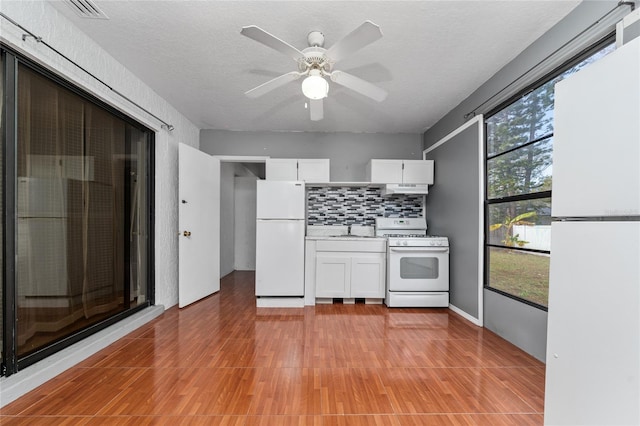 kitchen featuring sink, white appliances, white cabinets, and backsplash