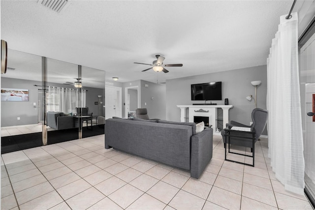 living room with ceiling fan, light tile patterned floors, and a textured ceiling